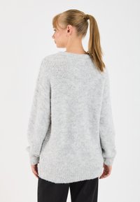 Pull en maille gris clair avec une coupe décontractée, des poignets côtelés et un dos long. Texture douce avec un motif de tissage légèrement ouvert.