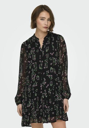 Schwarzes Kleid aus transparentem Stoff, mit floralen Mustern in Lila und Grün, Knopfleiste, langen Ärmeln, plissiertem Rock und einem weichen Kragen.