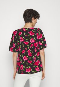 Blusa preta de mangas curtas, com um vibrante padrão floral rosa e folhas verdes. Tecido suave com um corte descontraído.