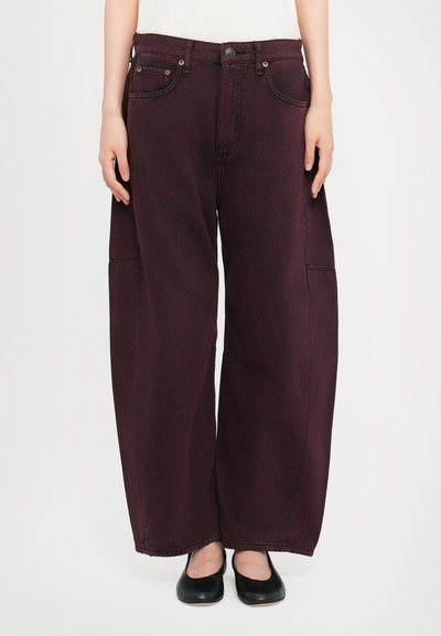 Baggy, dark burgundy denim jeans with a high waist, large side pockets, and visible stitching. Paired with black flat shoes.