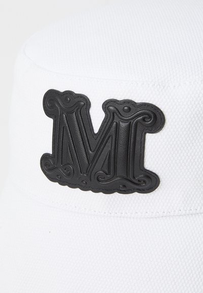Valkoinen hattu, jossa on teksturoitu pinta, ja jonka etupuolella on kohotettu musta "M"-logo, jossa on monimutkainen yksityiskohtaisuus.