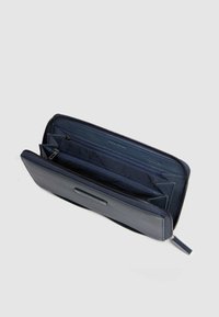 Portafoglio in pelle blu navy con chiusura a zip, molteplici scomparti per carte e due tasche con zip per un'organizzazione sicura. Dettaglio della superficie testurizzata.