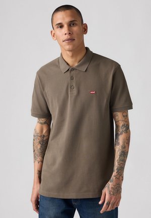 Brown polo shirt in cotton blend, featuring a classic collar, three buttons, and a red Levi's logo on the left chest. Plain design.