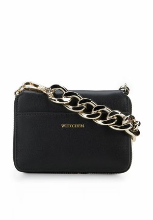 Sac à main en cuir noir avec une bandoulière en chaîne dorée, doté d'une fermeture éclair et d'un logo embossé. Texture lisse avec un design minimaliste.
