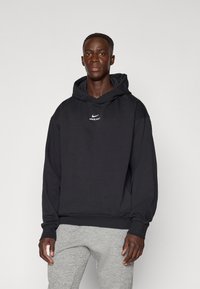 Černá mikina Nike Pro s logem na přední stran�ě, dlouhými rukávy a kapucí se stahovací šňůrkou. Měkká tkanina s volným střihem a žebrovanými manžetami.