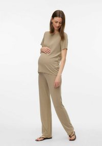 Top de maternidad beige con mangas cortas, tejido texturizado, combinado con pantalones de pierna ancha a juego, ambos con un corte relajado y bordes sin acabados.