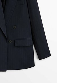 Blazer bleu marine foncé à fines rayures, avec deux boutons noirs, un revers cranté et une poche à rabat sur le devant côté droit.