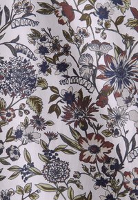 Motif de tissu floral avec des fleurs et des feuilles assorties en bleu marine, rouge profond, vert olive et crème sur un fond beige clair.