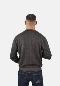 Maglione con zip, lavorato a maglia di colore grigio scuro con motivo testurizzato. Presenta polsini e orlo a coste, visto da dietro. Vestibilità e stile casual.