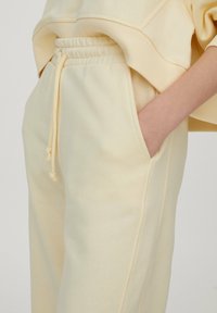 Jasnożółte dresy o miękkiej teksturze, z kieszeniami bocznymi oraz elastycznym pasem ze sznurkiem. Prosty krój i luźny fason.