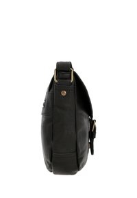 Zwarte leren crossbody tas met verstelbare riem, messing hardware en een voorflap sluiting, zijaanzicht op een witte achtergrond.