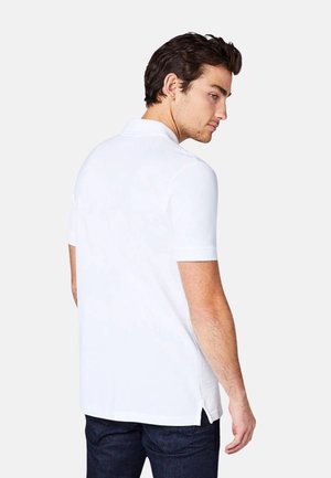 Wit polo-shirt met korte mouwen en een ontspannen pasvorm. Voorzien van zijsplitten aan de onderkant en een klassiek kraagontwerp. Zachte textuur.