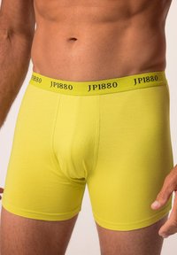 Boxers amarillos brillantes hechos de una tela suave y elástica. Presentan una cinturilla negra con el logotipo "JP1880". Tienen una forma ajustada y una textura suave.