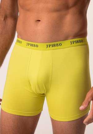 Boxers lumineux jaunes fabriqués en tissu doux et extensible. Dotés d'une ceinture noire avec le logo "JP1880". Forme ajustée et texture lisse.