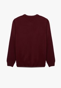 Burgundin neulepaita pitkillä hihoilla, pyöreällä pääntiellä ja ribbauslahkeilla. Sujuva pinta, yksinkertainen muotoilu ja ei näkyviä koristeita.