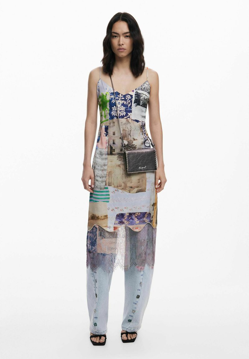Patchwork maxi dress in mixed textures and colors, featuring a v-neck, layered design, and sheer accents, paired with dark crossbody bag.