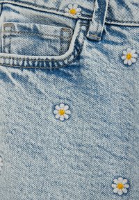 Hele sinine teksariie, millel on väikesed valge ja kollase tikandiga õied. Nähtavad õmblused ja väike eesmine tasku detail.