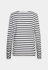 Long-sleeve shirt in white and black stripes, made of soft fabric. Features a round neckline and a relaxed fit with side slits.