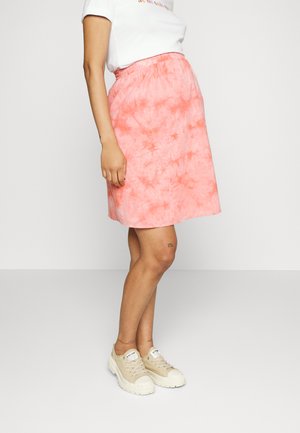Saia em A com padrão tie-dye rosa, com cintura elástica, apresentando uma textura suave e um design até ao joelho, combinada com ténis bege.