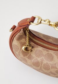 Borsa a mano marrone con motivo, realizzata in materiale testurizzato, dotata di dettagli in oro, tracolla in pelle e una cerniera con un ciondolo.
