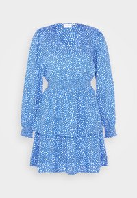 Robe bleue avec taille smockée, manches longues, jupe à volants et motif à pois blancs sur un tissu léger.