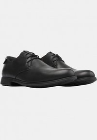 Pantofii din piele neagră au o textură netedă, vârf rotund, un design cu șireturi și talpă din cauciuc cu accente roșii pe găurile pentru șireturi.