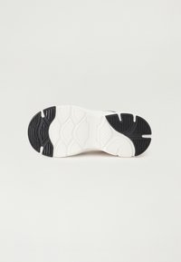 Skoesål med teksturert svart gummi og hvite detaljer. Designet inkluderer mønstrede spor for grep og stabilitet.