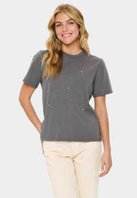 Grå bomullströja med klassisk rund hals, korta ärmar och prydd med små vita nitar i ett spritt mönster.