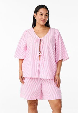 Loungewear-Set aus pink-weiß gestreifter Baumwolle, bestehend aus einem V-Ausschnitt-Oberteil mit kurzen Ärmeln und vornem Knoten, kombiniert mit passenden Shorts.