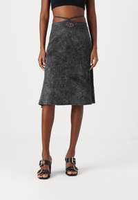 Schwarzer, knielanger Rock aus strukturiertem Stoff mit einer leicht ausgestellten Form. Verfügt über einen geflochtenen Gürtel und ovale dekorative Beschläge an der Taille.