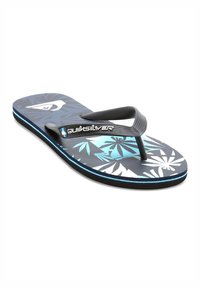 Tongs noires et bleues avec un motif floral, semelle текстurée et rayures d'accent bleu contraste le long de la semelle. Logo Quiksilver inclus.