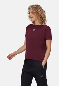 Burgundowa koszulka z krótkim rękawem i okrągłym dekoltem, z okrągłym białym logo na klatce piersiowej, w zestawie z czarnymi spodniami z akcentem logo.
