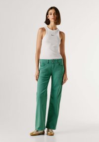 Zelene široke hlače iz bombaža z gumbi spredaj, stranskimi žepi in v kombinaciji z belim rebrastim topom.
