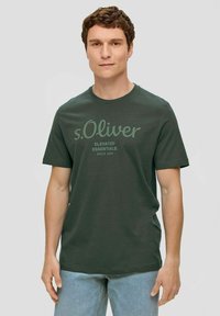 Dunkelgrünes Baumwoll-T-Shirt mit kurzen Ärmeln, Rundhalsausschnitt und mittig platziertem s.Oliver Logo-Druck in hellerem Grün. Lässige, lockere Passform.