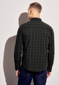 Tmavě zelená košile s dlouhým rukávem a kostkovaným vzorem, se rovně střiženým spodním lemem, knoflíkovými manžetami a klasickým límcem.