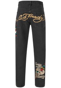 Zwarte denim jeans met gouden "Ed Hardy" logo, kleurrijke schedel- en dolkgraphics, en een banner met de tekst "Death Before Dishonor."