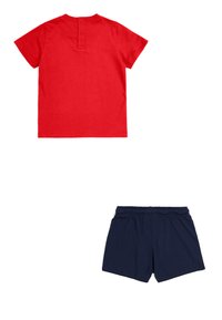 Camiseta de algodón roja con mangas cortas y detalle de botones en la parte posterior, combinada con pantalones cortos de algodón azul marino con cintura elástica.