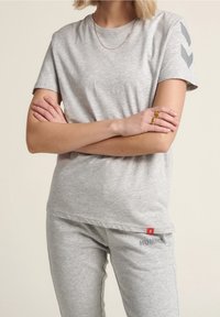 Szara bawełniana koszulka z krótkim rękawem, z okrągłym dekoltem i szarymi wzorami w jodełkę na rękawach. Zestawiona z szarymi dresami.