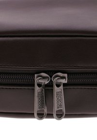 Bolso sintético marrón con una superficie texturizada, que cuenta con doble cremallera metálica y etiquetas de marca para un cierre seguro y un acceso fácil.