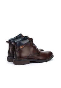 Bottines en cuir marron, avec une texture lisse, un bout rond, un design à lacets et des accents bleus contrastants sur le col et la doublure.