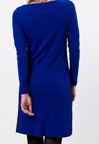 Vestito lungo a maniche blu in un design aderente con pannelli laterali neri a contrasto e tessuto morbido e liscio. Presenta un ampio scollo e una lunghezza media.