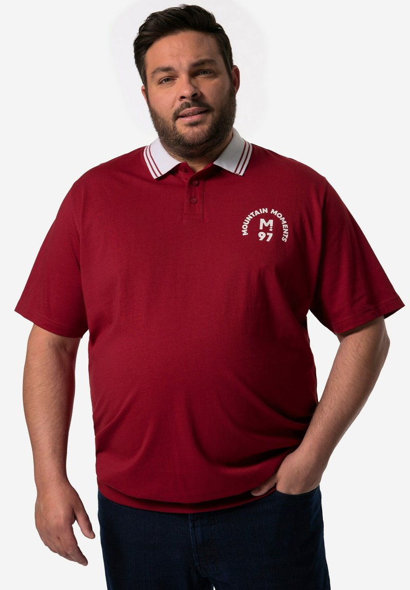 Červené polo tričko s límečkem, který má kontrastní bílé pruhy, logo na levé straně, krátké rukávy a měkkou texturu.