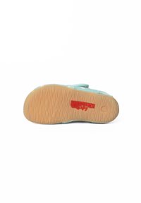 Lichtblauwe schoen met een bovenwerk van textuurstof en rubberen zool. De zool heeft golvende groeven en een rood logo. Verstelbare band voor een veilige pasvorm.