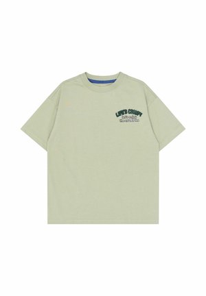 Lysegrøn T-shirt med korte ærmer og rund hals med lille mørkegrøn og hvid tekst på venstre bryst, der lyder "Lad os nyde krummerne."
