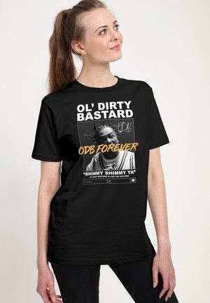 Kvinde med hestehale iført sort T-shirt med sort-hvidt foto af Ol' Dirty Bastard med tekst "ODB Forever" og "Shimmy Shimmy Ya."