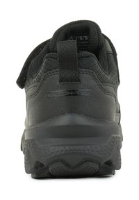 Schwarzer Sportschuh mit einem strukturierten Lederoberteil, gepolstertem Kragen, Klettverschlussriemen und einer strukturierten Gummisohle für Halt.