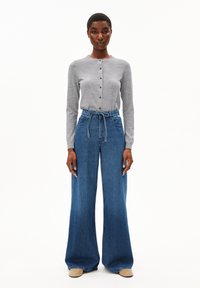 Cardigan gris à manches longues avec fermeture à boutons et pantalon en denim bleu à jambes larges assorti, doté d'une taille à cordon de serrage et d'une texture lisse.