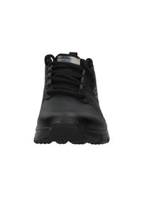 Scarpe sportive nere con una parte superiore in sintetico liscio, punta rotonda e suola in gomma testurizzata. Presentano lacci e un logo discreto sui lati.