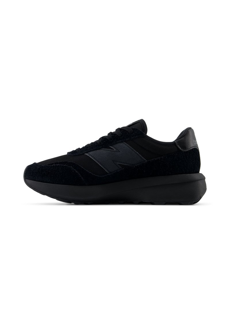 Fekete New Balance sportcipő texturált velúrból és hálóból készült felsőrésszel, vastag párnázott talppal, oldalt és a sarkán logóval, oldalnézetből bemutatva.