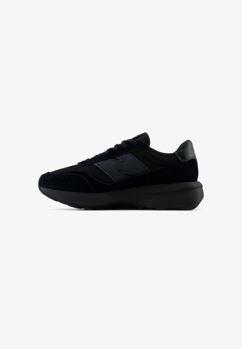 Fekete New Balance sportcipő texturált velúrból és hálóból készült felsőrésszel, vastag párnázott talppal, oldalt és a sarkán logóval, oldalnézetből bemutatva.